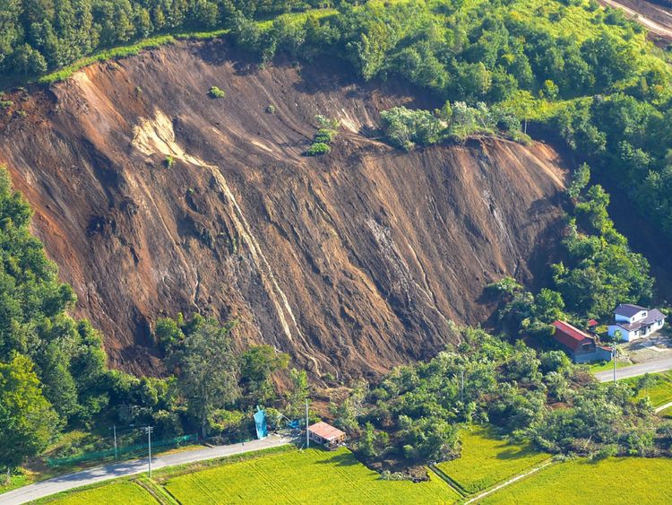 Cette photo montre une vue aérienne de maisons endommagées par un glissement de terrain dans la ville d'Atsuma, préfecture d'Hokkaido, le 6 septembre 2018, après le tremblement de terre qui a frappé l'île d'Hokkaido, au nord du Japon