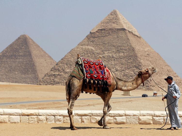 Un homme attend les touristes pour louer son chameau devant les grandes pyramides de Gizeh à la périphérie du Caire, en Egypte, le 31 août 2016. Photo prise le 31 août 2016