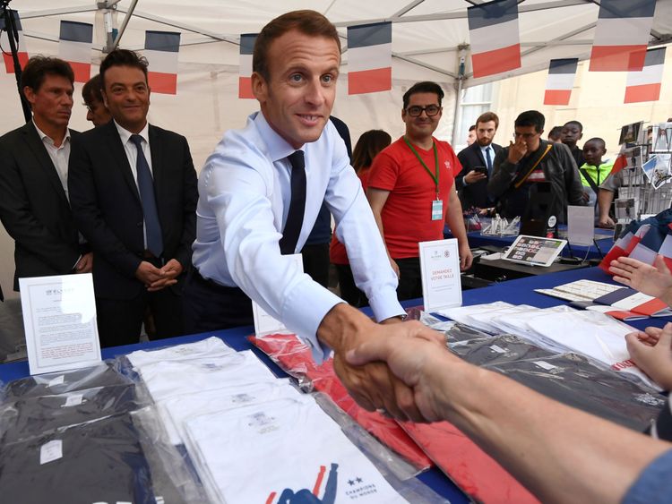 Le président français Emmanuel Macron serre la main avec les visiteurs à côté des articles en vente à l'Elysée
