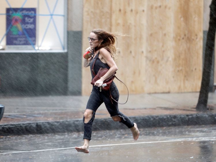 Une femme passe devant les guichets des magasins pendant les premières pluies avant l'arrivée de l'ouragan Florence à Wilmington, en Caroline du Nord.