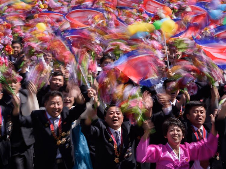 Les participants agitent des fleurs alors qu’ils défilent devant un balcon où le chef de la Corée du Nord, Kim Jong Un, regardait, lors d’un rassemblement sur la place Kim Il Sung à Pyongyang, le 9 septembre 2018.