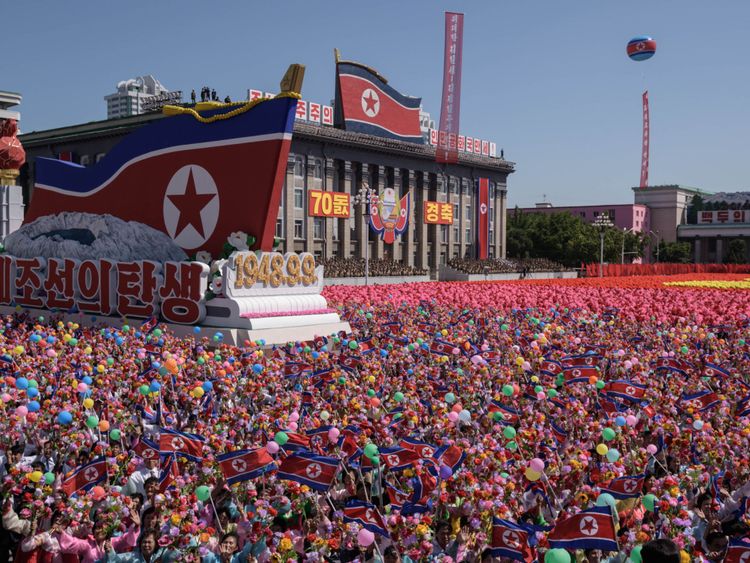 Les participants agitent des fleurs alors qu’ils défilent devant un balcon où le chef de la Corée du Nord, Kim Jong Un, regardait, lors d’un rassemblement sur la place Kim Il Sung à Pyongyang, le 9 septembre 2018.