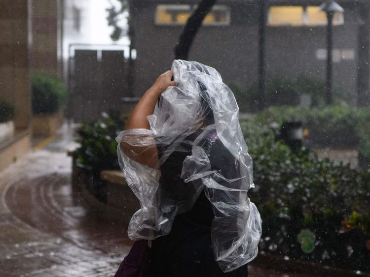 Un piéton utilise un poncho en plastique lors du Super Typhon Mangkhut à Hong Kong le 16 septembre 2018. - Le typhon Mangkhut a secoué Hong Kong en Chine continentale le 16 septembre, blessant des dizaines et envoyant des gratte-ciels et déchirant une bande de destruction à travers son cœur agricole. (Photo par Anthony WALLACE / AFP) (Le crédit photo devrait être ANTHONY WALLACE / AFP / Getty Images)

