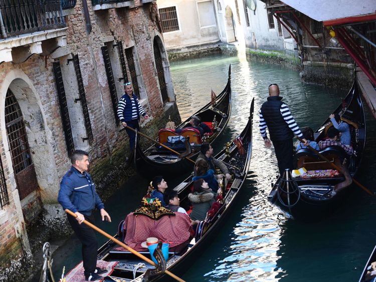 Des touristes assis dans des gondoles sur le Grand Canal à Venise