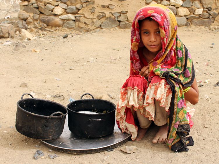 Un enfant yéménite déplacé est assis à côté de pots de nourriture dans un camp de fortune dans le district nord de la province de Hajjah, au Yémen, le 7 juillet 2018