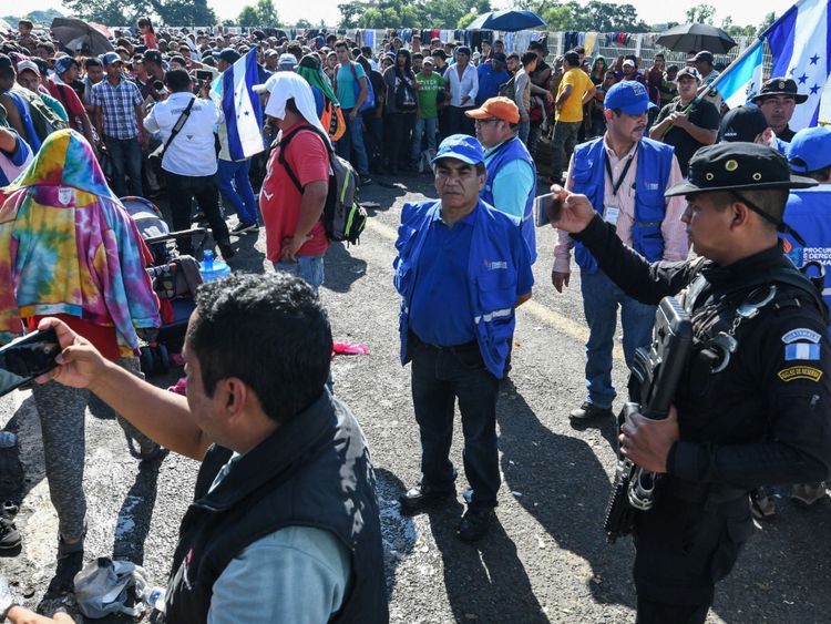Un policier guatémaltèque prend une photo alors que des migrants honduriens se rendent aux États-Unis