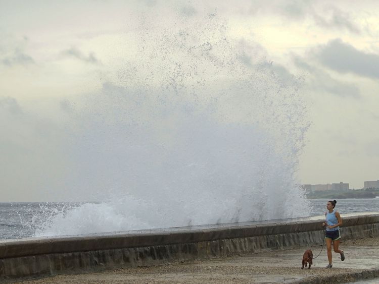 Une femme court avec un chien alors que les vagues éclaboussent le front de mer à La Havane, après le passage de l'ouragan Michael dans l'ouest de Cuba, le 9 octobre 2018