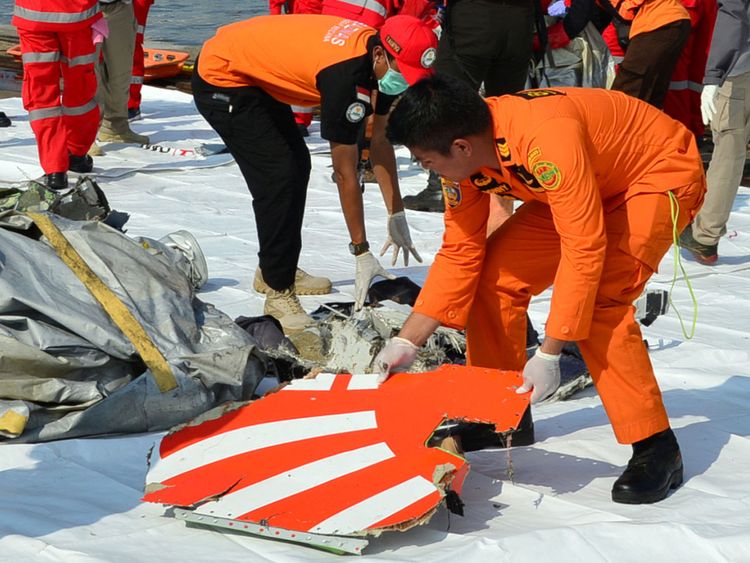 Les membres de l'équipe de secours organisent l'épave et montrent une partie du logo du vol JT610 de Lion Air