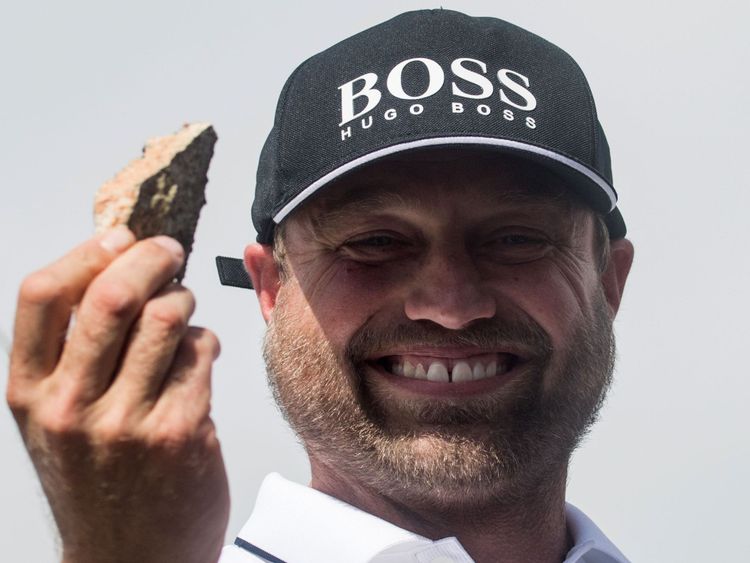 Alex Thomson lève un morceau de roche qu'il a ramassé après sa collision