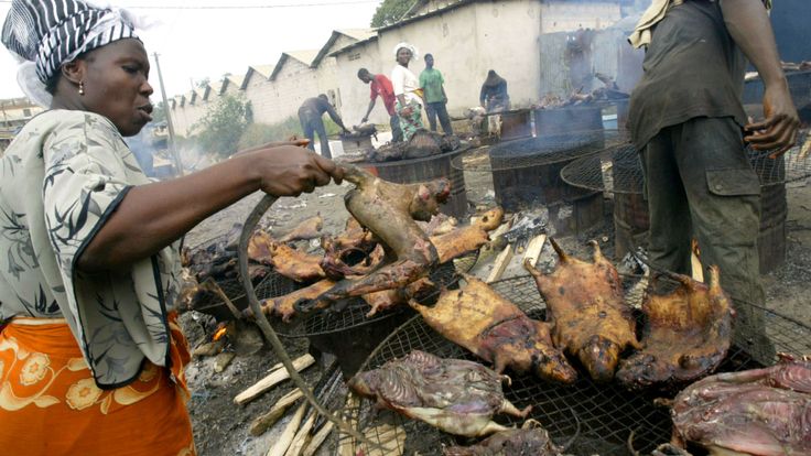 Une femme fumant de la viande de brousse sur un marché en Afrique