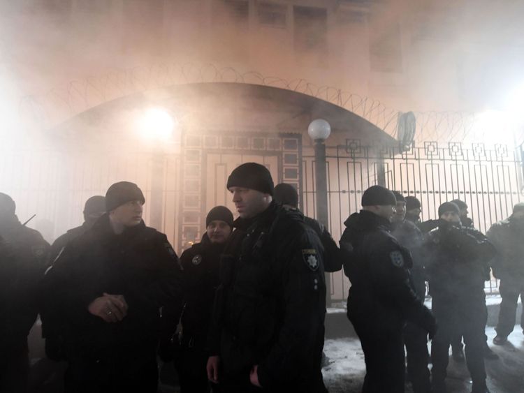 Des policiers se tiennent devant l'ambassade de Russie à Kiev à la fin du 25 novembre 2018, tandis que des manifestants manifestent la fumée lors d'une manifestation à la suite d'un incident survenu dans la mer Noire au large de la Crimée annexée à Moscou.