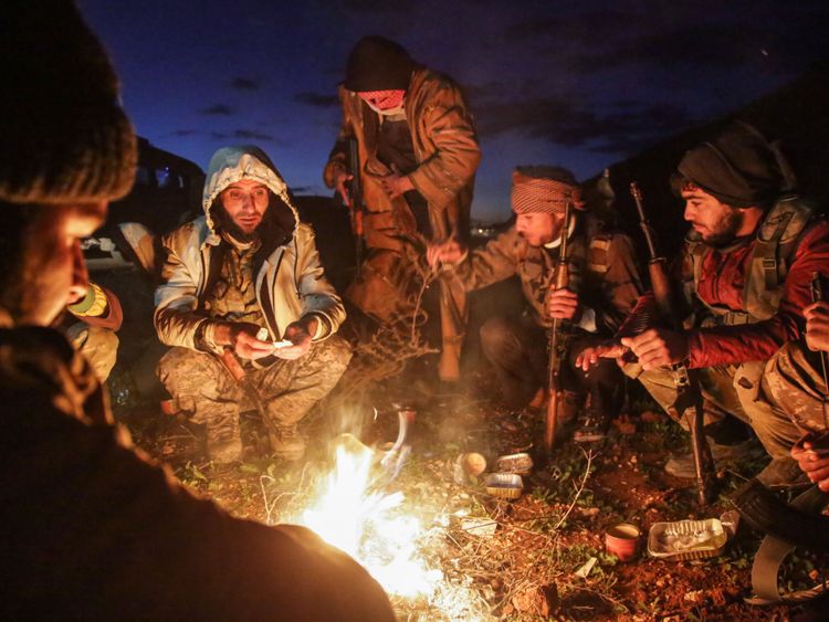 Des combattants syriens soutenus par la Turquie se réchauffent autour d'un feu près de Manbij