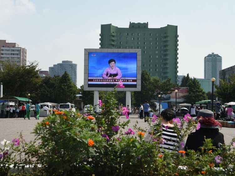 Mme Ri annonce la nouvelle sur un grand écran devant la gare de Pyongyang