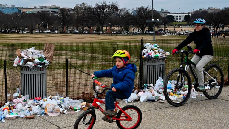 La Maison Blanche apparaît à l'arrière-plan alors que les gens passent à vélo devant les ordures non ramassées dans le National Mall, en raison de la fermeture partielle du gouvernement américain le 2 janvier 2019 à Washington, DC