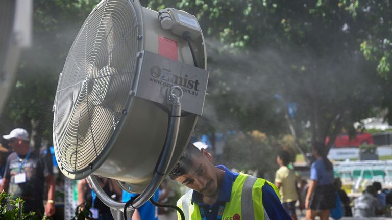 Un homme se rafraîchit devant un fan de brume pour se soulager de la chaleur du 12ème jour du tournoi de tennis de l'Australian Open à Melbourne