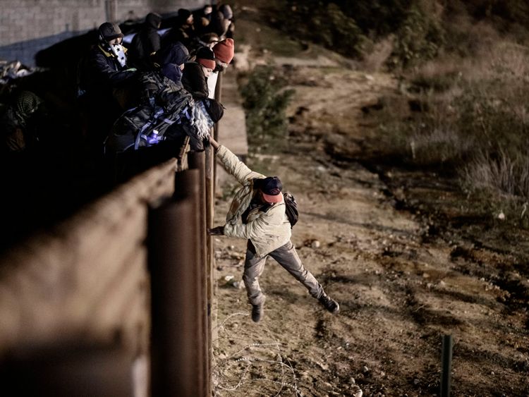 Un migrant franchit la barrière frontalière pour se rendre du côté américain à San Diego, en Californie, depuis Tijuana