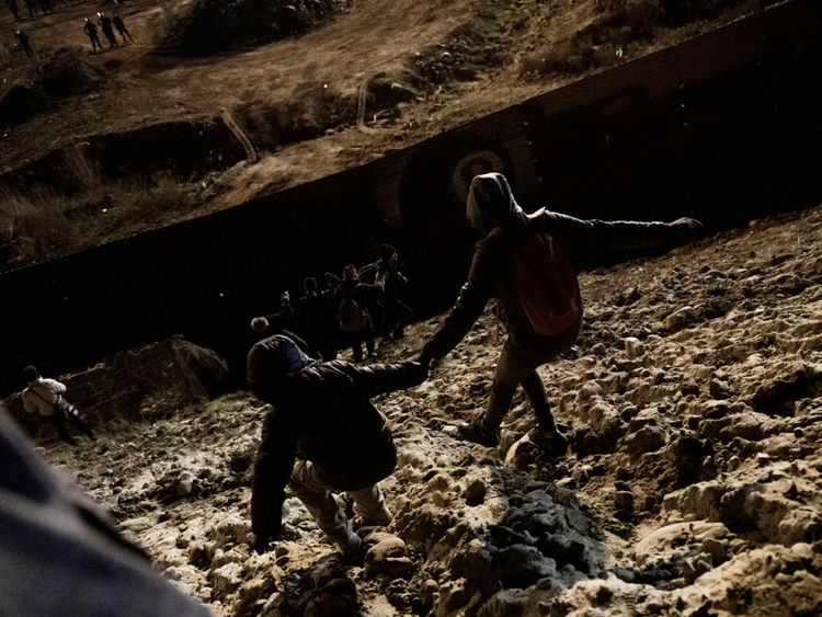 Des migrants se dirigent vers la barrière frontalière alors qu'ils tentent d'entrer du côté américain à San Diego, en Californie, en provenance de Tijuana, au Mexique