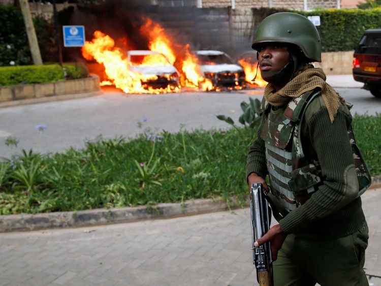 Un policier passe devant des voitures en feu sur le lieu de l'incident, où des explosions et des coups de feu ont été entendus dans l'enceinte de l'hôtel Dusit, à Nairobi.