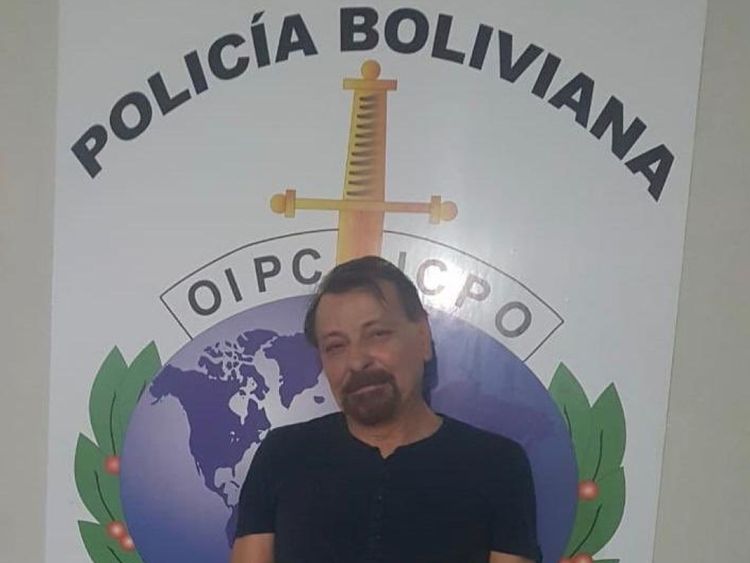 Cesare Battisti se tient devant un panneau de police de la Bolivie alors qu'il est arrêté