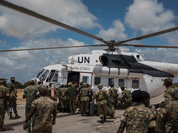 Des membres du 17e groupement tactique des forces de défense du peuple ougandais (UPDF) servant dans la mission de l'Union africaine en Somalie (AMISOM) chargeant un hélicoptère des Nations Unies à l'extérieur de la base d'opérations avancée de l'AMISOM, Barawe, le 10 octobre 2016