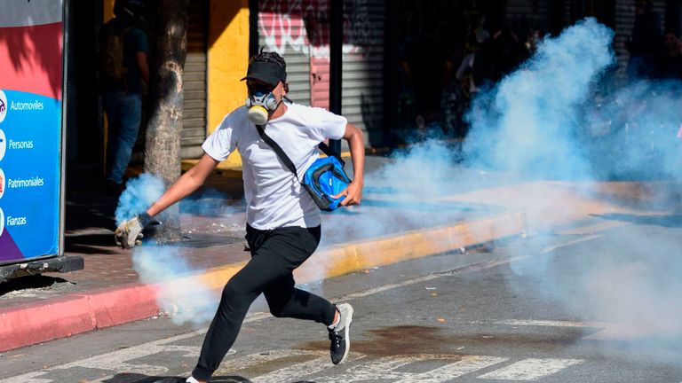 Un manifestant de l'opposition court avec une cartouche de gaz lacrymogène
