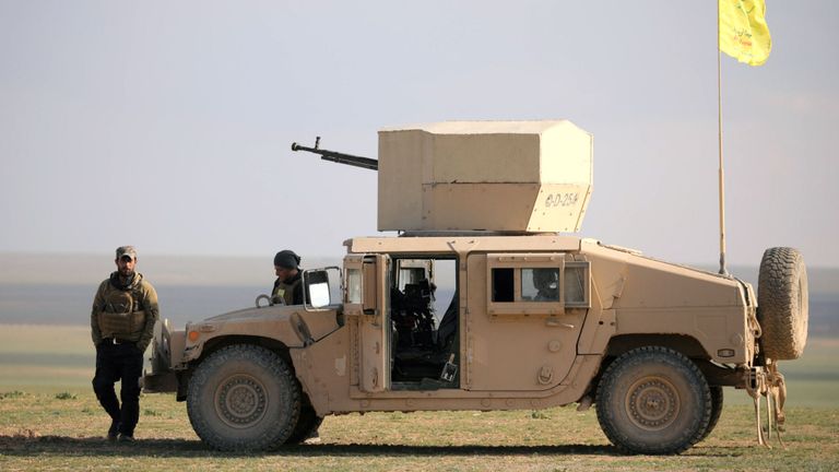 Un membre des Forces démocratiques syriennes (SDF) marchant à proximité d'un véhicule militaire près de Baghouz