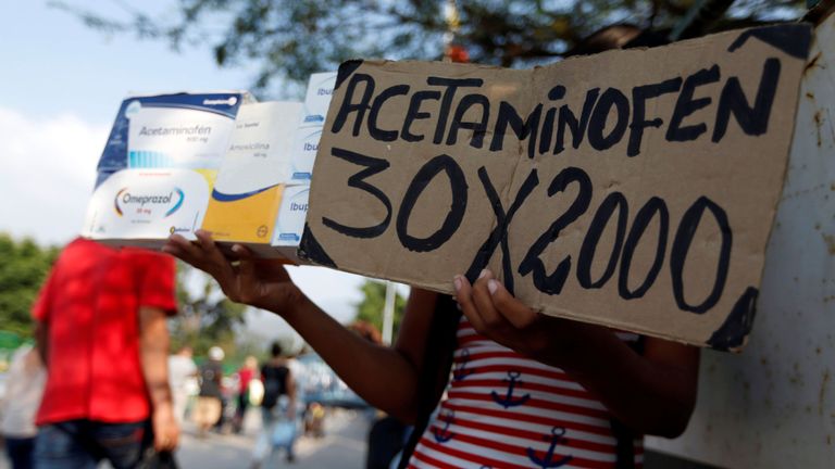 Une femme tient une pancarte "Acétaminophène 30 x 2000" sur le pont international de Simon Bolivar