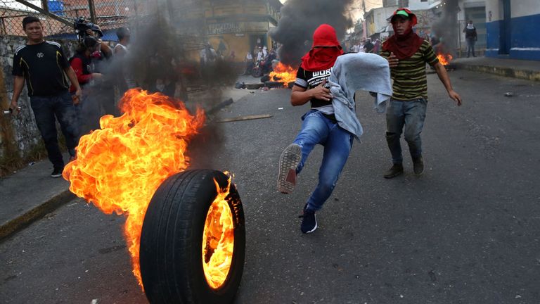 Un manifestant donne un coup de pied dans un pneu brûlant à Urena