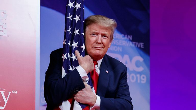 Le président Donald Trump étreint le drapeau américain alors qu'il arrive pour prendre la parole lors de la conférence d'action politique conservatrice, CPAC 2019, à Oxon Hill, dans le Maryland, le samedi 2 mars 2019. (AP Photo / Carolyn Kaster)