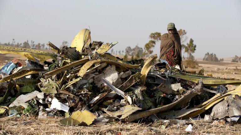 Une femme se tient près d'un tas de débris de l'épave d'Ethiopian Airlines