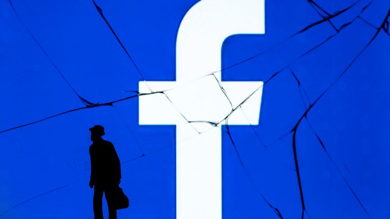Cette photo prise le 16 mai 2018 montre une figurine se tenant devant le logo du réseau social Facebook sur un écran fissuré d'un smartphone à Paris.