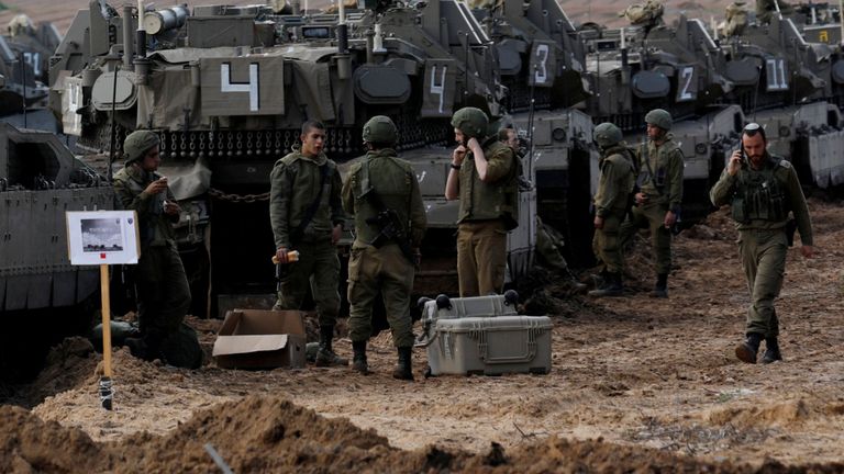 Les soldats israéliens discutent à côté du transport de troupes blindé près de la frontière avec Gaza.
