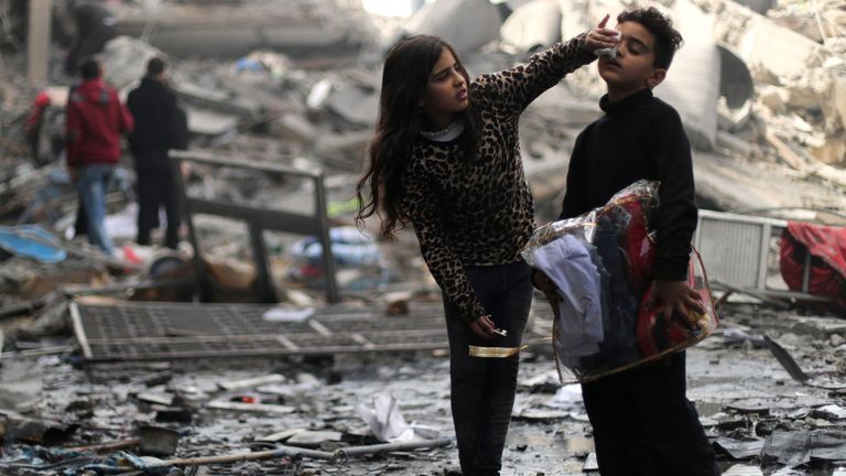 Une fillette palestinienne nettoie le visage de son frère devant leur maison détruite après une frappe de missile israélienne