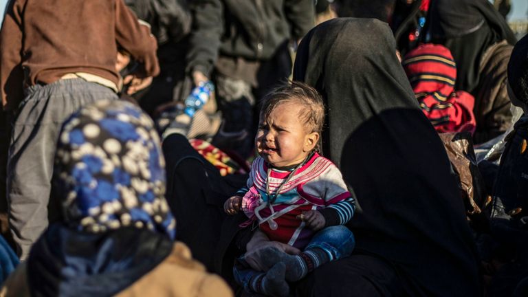 Des femmes et des enfants attendent d'être fouillés par des membres du SDF