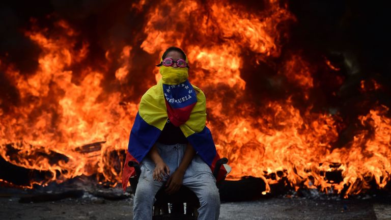 Un militant de l'opposition vénézuélienne assis devant une barricade en feu 