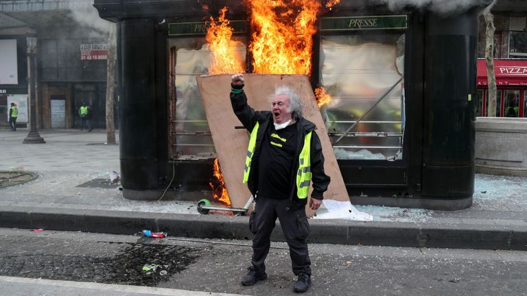 Un manifestant devant un kiosque en feu