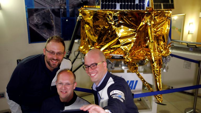 Les gens de SpaceIL et Israel Aerospace Industries (IAI) réalisent un selfie devant un modèle de vaisseau spatial Beresheet
