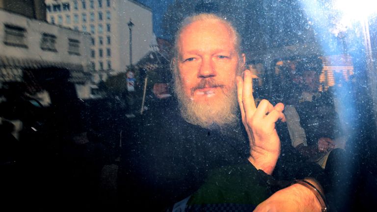 Julian Assange fait des gestes aux véhicules depuis un véhicule de la police à son arrivée devant le tribunal de Westminster Magistrates 