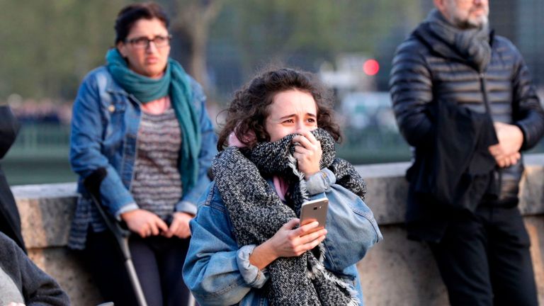 Une femme réagit en regardant les flammes engloutir le toit de la cathédrale Notre-Dame à Paris 