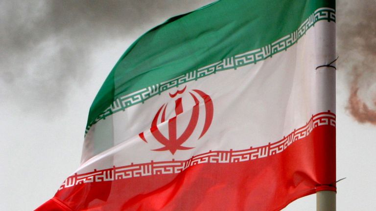 Une fusée éclairante sur une plate-forme de production pétrolière dans les gisements de Soroush est vue le long d'un drapeau iranien dans le golfe Persique, Iran, 25 juillet 2005
