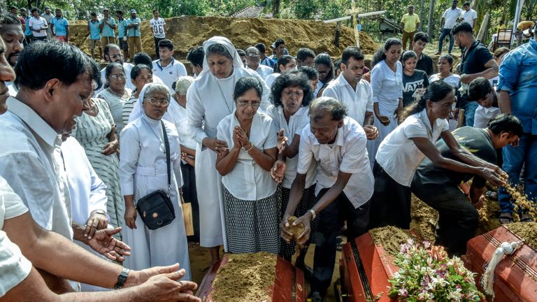 Des familles de morts offrent leurs prières lors des funérailles au village de Katuwapity