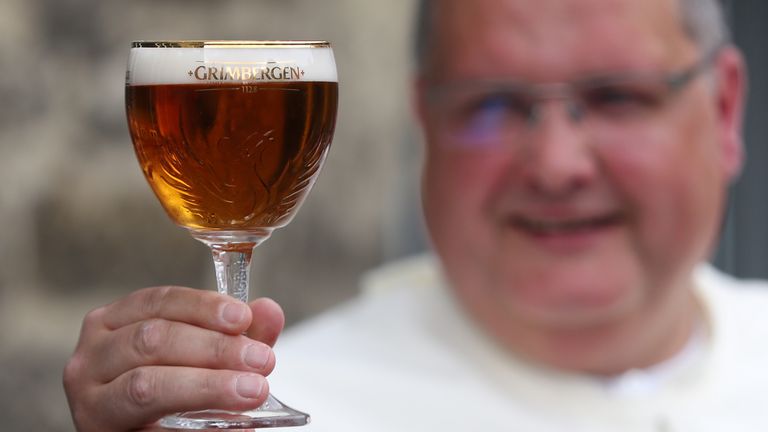 Le père Karel de Norbertine pose avec une bière Grimbergen, symbolisée par un phénix, dans la cour de l'abbaye belge de Grimbergen avant d'annoncer que les moines retourneront à la brasserie après une pause de deux siècles, à Grimbergen, Belgique, le 21 mai 2019. REUTERS / Yves Herman