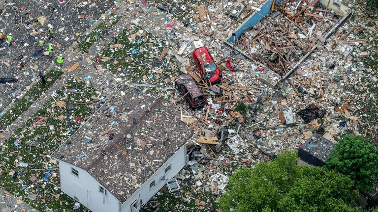 Véhicules endommagés à côté des débris de l'explosion d'une maison