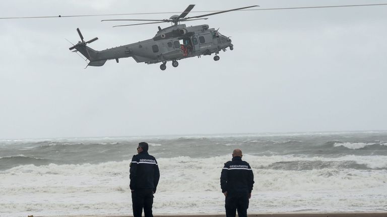 Deux gendarmes observent un hélicoptère de l'armée de l'air française survolant une plage aux Sables-d'Olonne