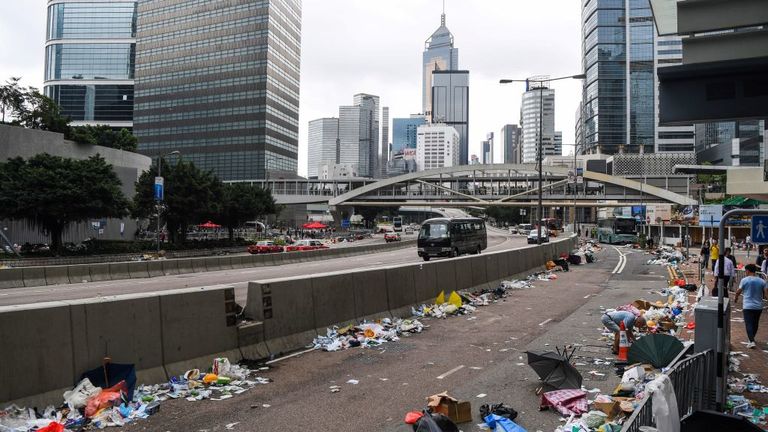 Les gens marchent dans une rue pleine de débris un jour après une manifestation contre une proposition de loi controversée sur l'extradition à Hong Kong le 13 juin 2019. - Les marchés asiatiques ont encore chuté le 13 juin, Hong Kong subissant une deuxième journée consécutive de lourdes pertes alors que les investisseurs s'inquiètent sur l’impact des manifestations dans la ville et envisage d’adopter une loi controversée autorisant l’extradition vers la Chine. (Photo par Anthony WALLACE / AFP) (Le crédit photo devrait correspondre à ANTHONY WALLACE / AFP / Getty Images)