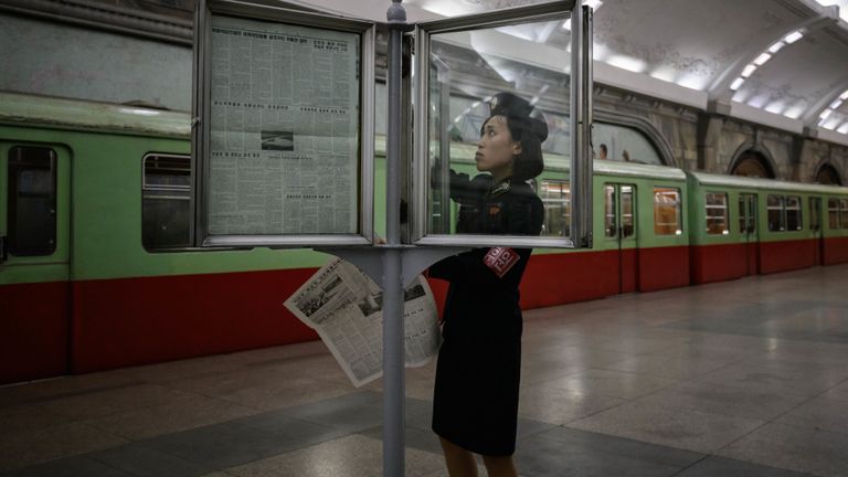 Une chef de train change de journal alors qu'elle met à jour un kiosque à journaux dans une station de métro de Pyongyang le 19 juin 2019, avant la visite du président chinois Xi Jinping dans la capitale nord-coréenne le 20 juin