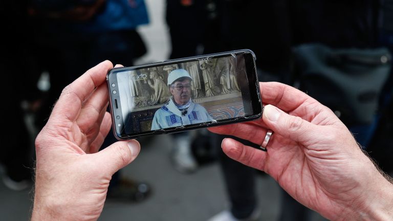 Une personne, munie d’un téléphone portable, regarde en direct l’émission de la première messe présidée par l’archevêque de Paris, Michel Aupetit, coiffée d’un casque de protection dans une chapelle latérale de la cathédrale Notre-Dame de Paris à la suite de l’incendie dévastateur du 15 avril, à Paris, le 15 juin 2019. - La cathédrale Notre-Dame de Paris accueillera sa première messe le 15 juin 2019, exactement deux mois après l'incendie dévastateur qui a secoué la France et le monde. Pour des raisons de sécurité, la messe présidée par l’archevêque de Paris Michel Aupetit
