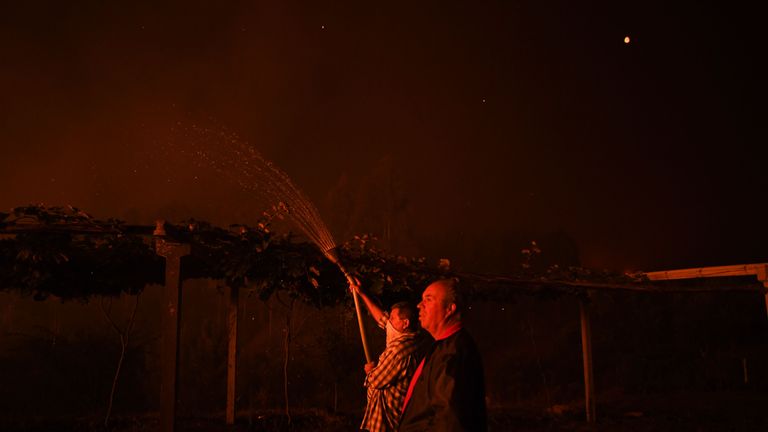 Un villageois tient un tuyau alors qu'un feu de forêt s'approche de son domicile à Amendoa à Macao, dans le centre du Portugal, le 21 juillet 2019. - Plus d'un millier de pompiers se sont battus pour contrôler les incendies dans le centre du Portugal qui ont forcé des évacuations de village, dans une région où Les pompiers ont été mobilisés pour lutter contre trois incendies dans la région montagneuse et fortement boisée de Castelo Branco, à 200 km au nord de Lisbonne, selon le site internet de la Protection civile. (Photo de PATRICIA DE MELO MOREIRA / AFP) (Le crédit photo devrait se lire PATRICIA DE MELO MOREIRA / AFP / Getty Images)