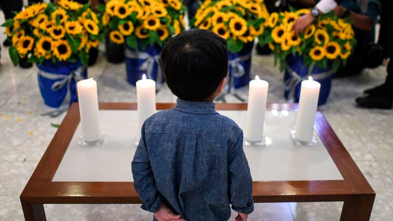 Un garçon debout devant des bougies et des fleurs lors d'une cérémonie commémorative pour les passagers morts à bord du vol MH17 de Malaysia Airlines, abattu il y a cinq ans au Haut-commissariat de l'Australie à Kuala Lumpur, le 17 juillet 2019. (Photo par MOHD RASFAN / AFP) (Le crédit photo doit se lire MOHD RASFAN / AFP / Getty Images)