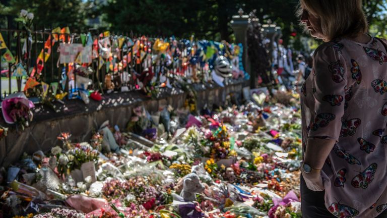 Une femme regarde des fleurs et des hommages près du mur des jardins botaniques le 24 mars 2019 à Christchurch, en Nouvelle-Zélande